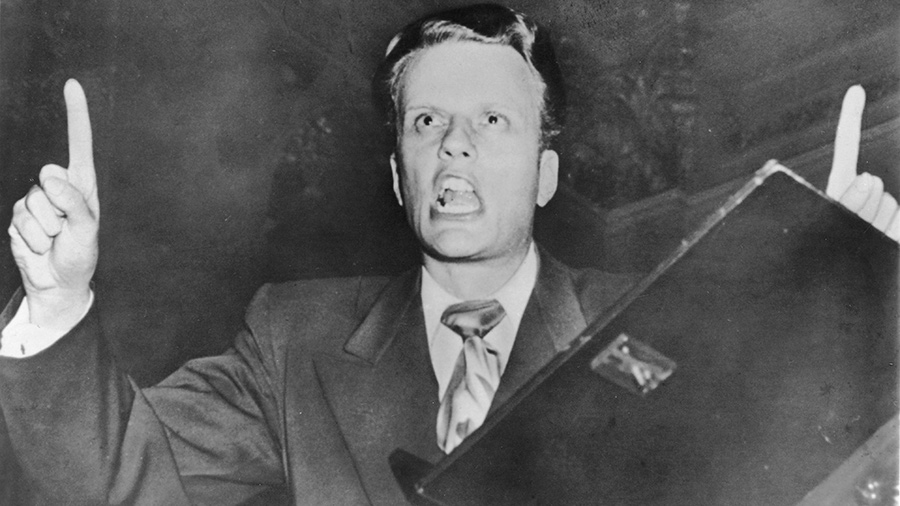 Billy Graham points upward as he preaches, early 1950s.