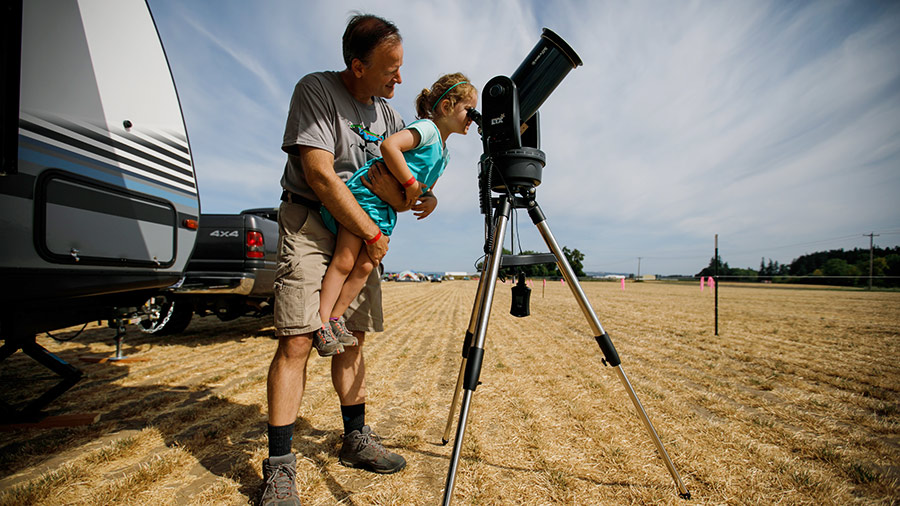 Jeff Thornton carries his daughter, Sammie, 4, to view the sun as they camp at French Prairie Gardens & Family Farm for a peaceful and unobstructed view of the upcoming total solar eclipse in St. Paul, Ore., on Aug. 20, 2017. 