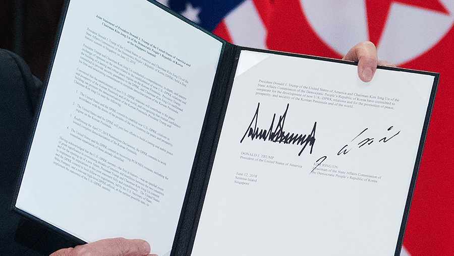 Close up of US President Donald Trump holding up a document signed by him and North Korea's leader Kim Jong Un following the signing ceremony.