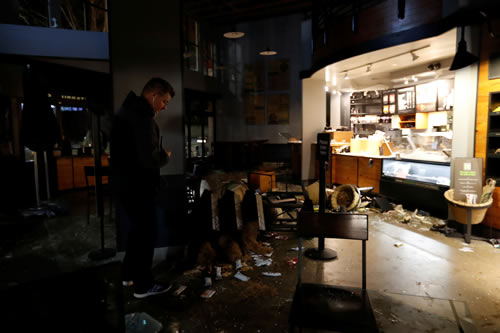 A worker surveys damage to a vandalized Starbucks after a protest turned violent at U.C. Berkeley over a scheduled speech by Milo Yiannopoulos in Berkeley, California.